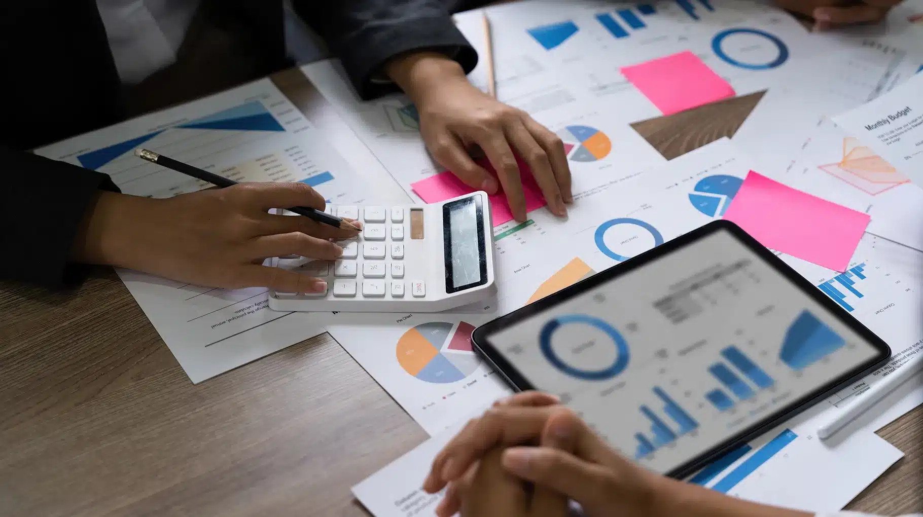 Business professionals collaborating at a table, surrounded by papers and calculators, focused on their work.