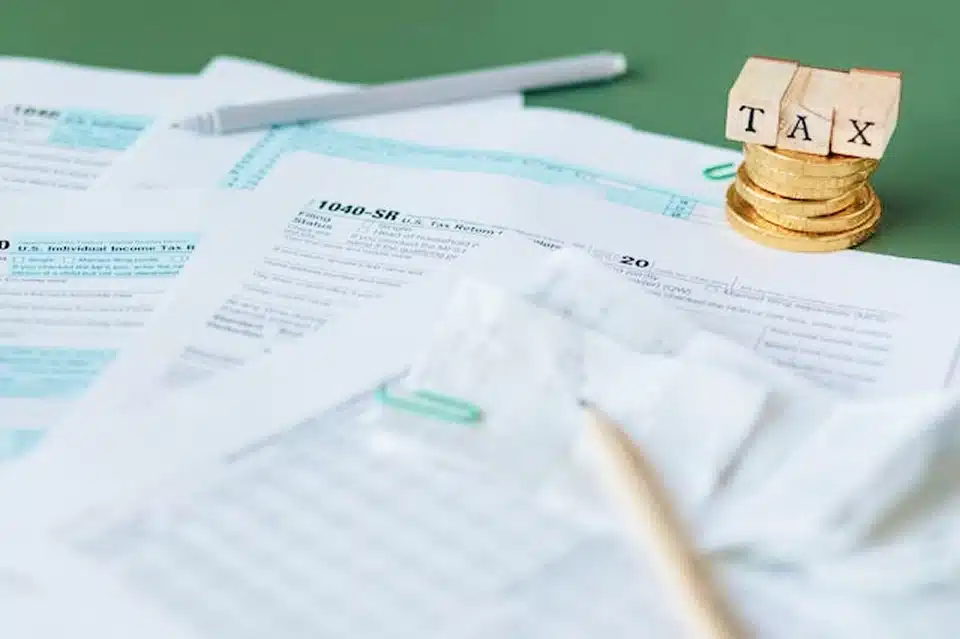 cluttered desk featuring tax documents, a calculator, and stacks of money, symbolizing financial planning and management.