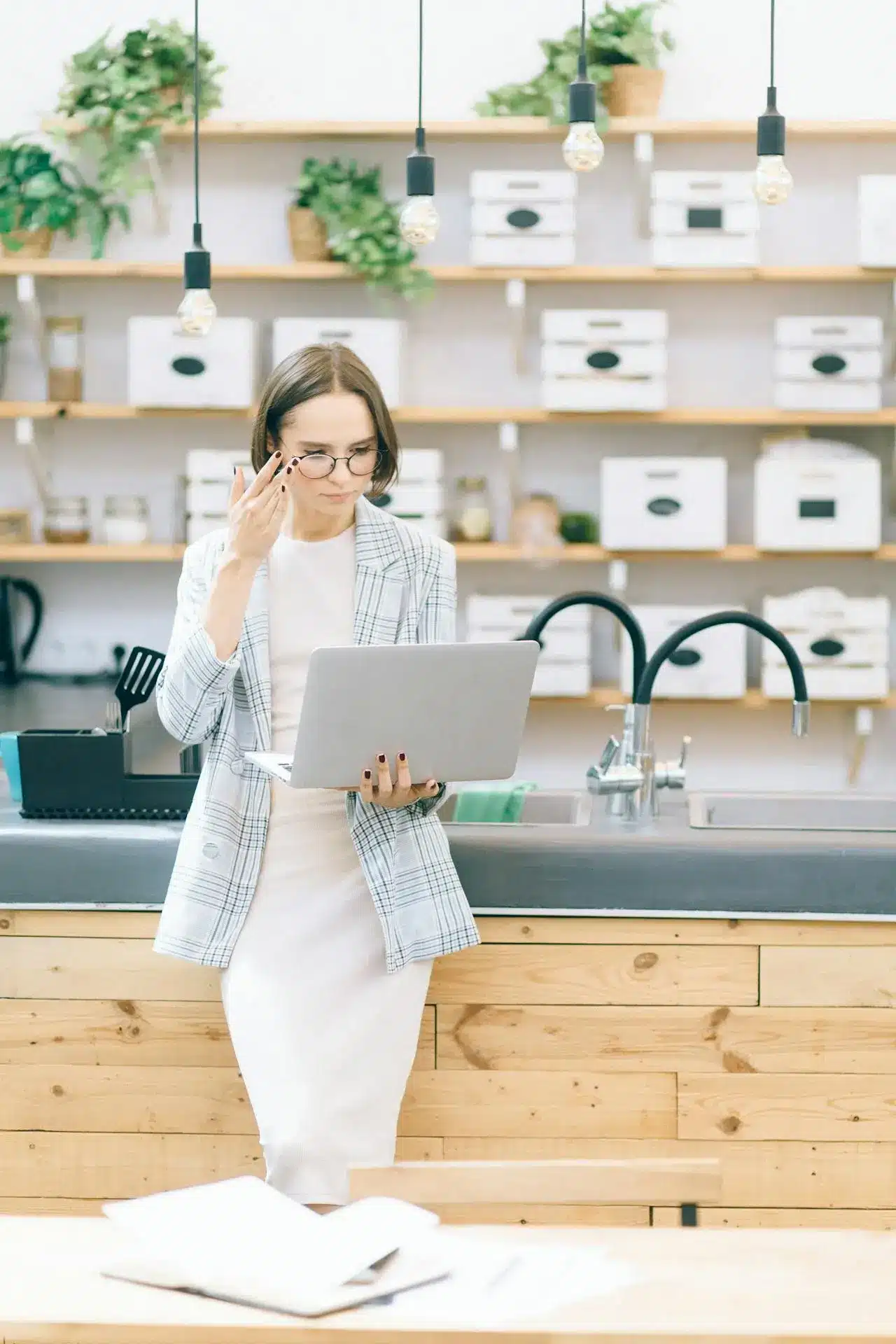 A woman in a suit stands confidently in front of a laptop, engaged in a professional setting.
