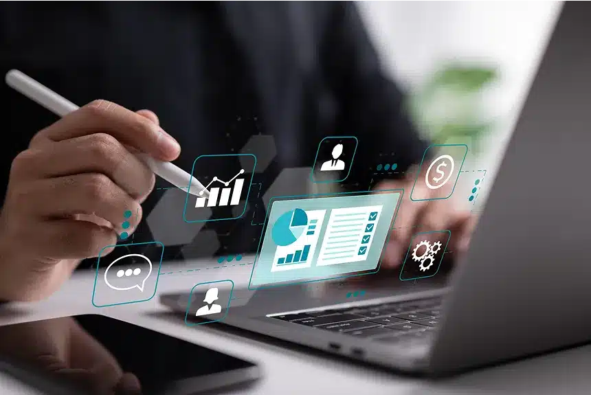A person typing on a laptop with various icons displayed on the screen, indicating active applications or files.