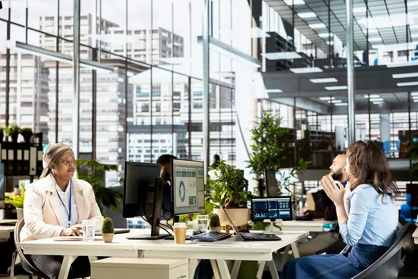 A group of diverse individuals engaged in discussion around a table in a modern office setting.