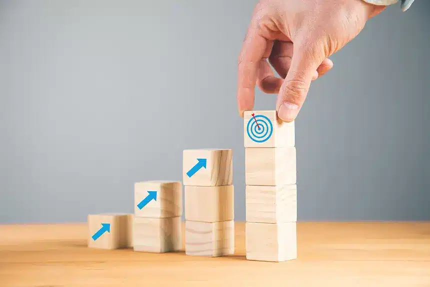 A person stacking wooden blocks with arrows on top, demonstrating a playful arrangement of shapes and directions.