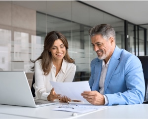 A business couple collaborating in a modern office setting, engaged in a discussion with documents on the table.