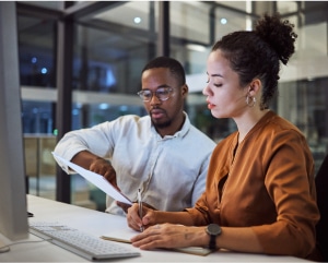 A man and woman collaborating on a project, focused and engaged in their work together.