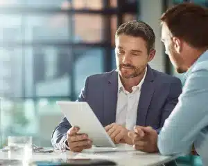 Two men in business suits examining a tablet together, engaged in a professional discussion.