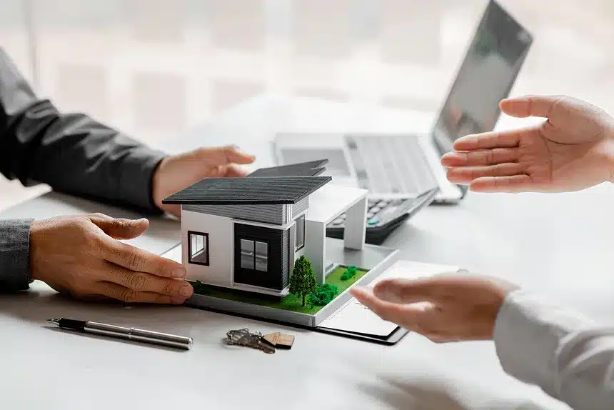 A man and woman are smiling while holding a small model of a house together.