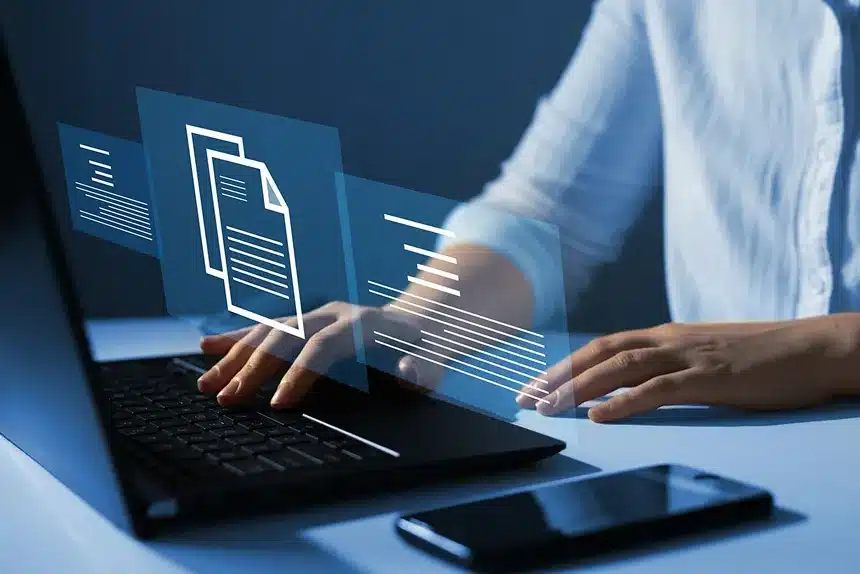 A woman working on a laptop, focused on a document displayed on the screen.