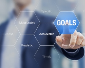 A businessman pressing the word "goals" on a digital screen, symbolizing ambition and strategic planning in business.