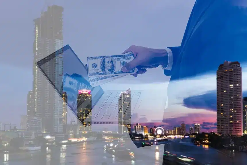 A man stands in front of a city, holding a laptop in one hand and cash in the other, symbolizing business and finance.