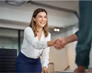 A woman and a man shaking hands in a professional office setting, symbolizing collaboration and agreement.