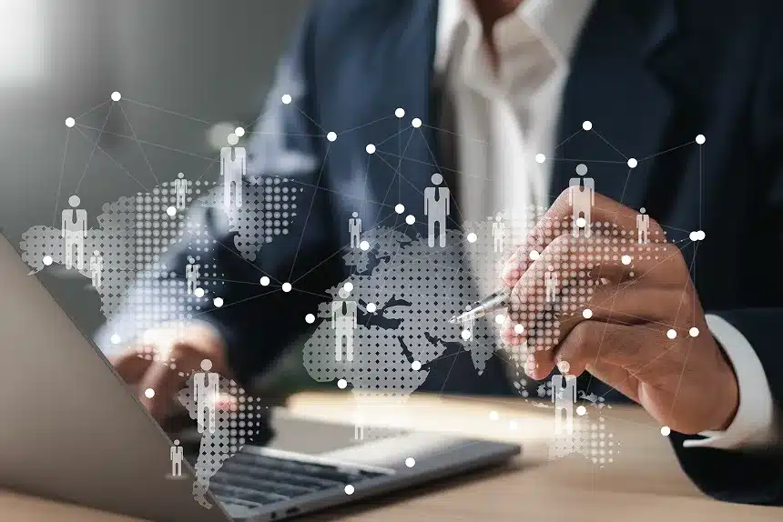 Businessman using a laptop, with a world map and social network connections displayed in the background.