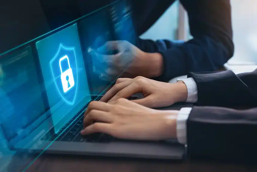 Businessman working on a laptop displaying a security icon on the screen, emphasizing cybersecurity in a professional setting.