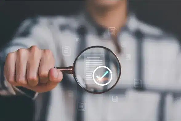 A man examines a check mark through a magnifying glass, symbolizing scrutiny and verification.