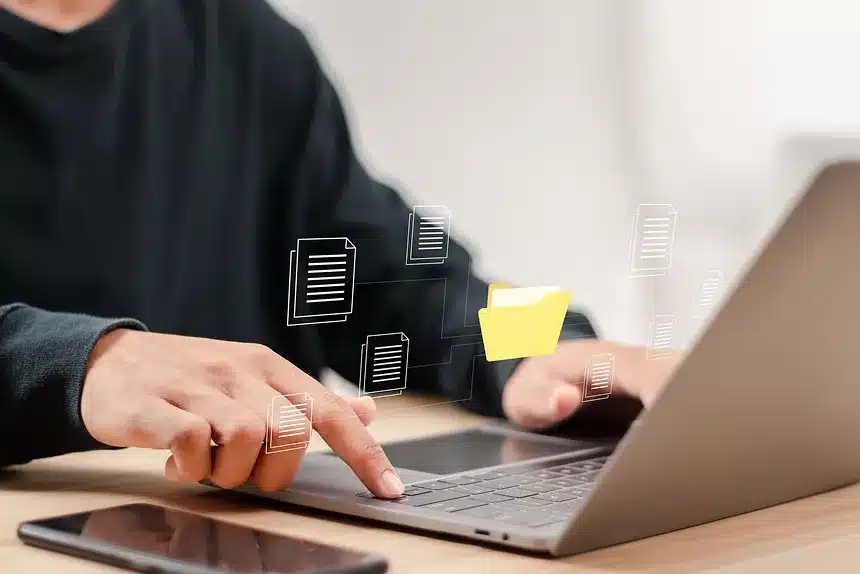 A person working on a laptop with a folder open on the screen, focused on their task.