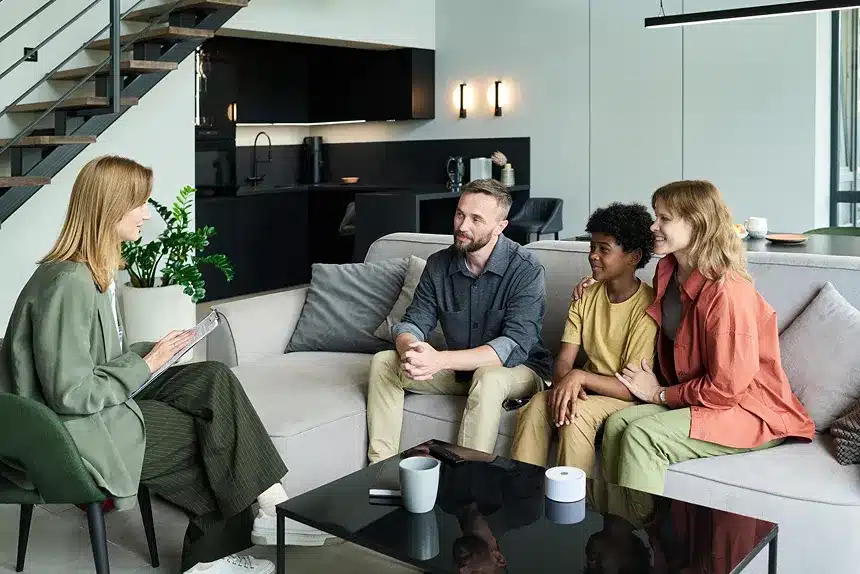 A group of four people sitting together on a couch in a cozy living room, engaged in conversation and laughter.