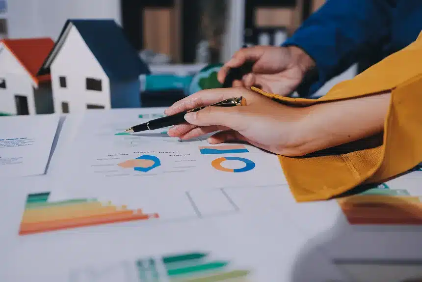 Businessman's hands on a document featuring a house illustration and various financial graphs.