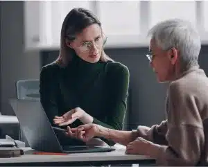 A person reviewing options for selecting a business coach, with notes and a laptop in a professional setting.
