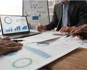 Business professionals analyzing graphs and documents collaboratively in a modern office setting.