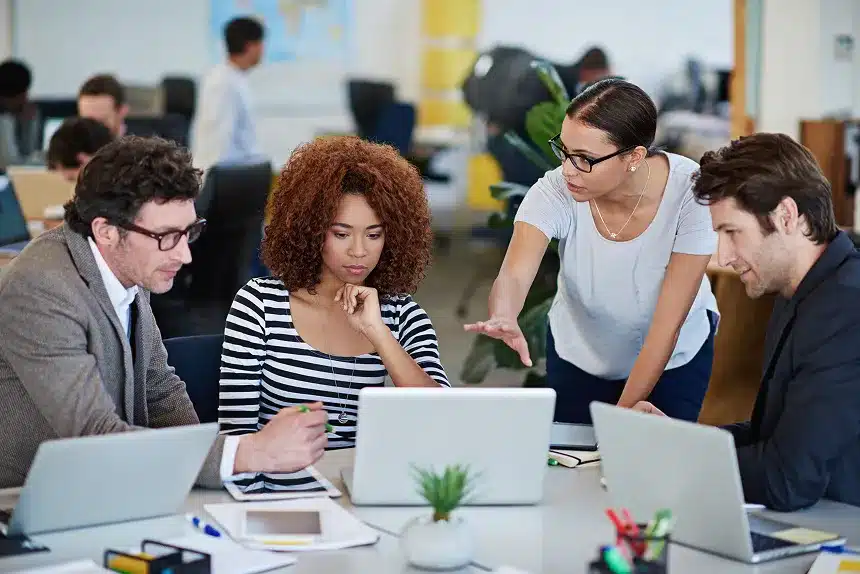 A diverse group of professionals collaborating on laptops in a modern office environment.