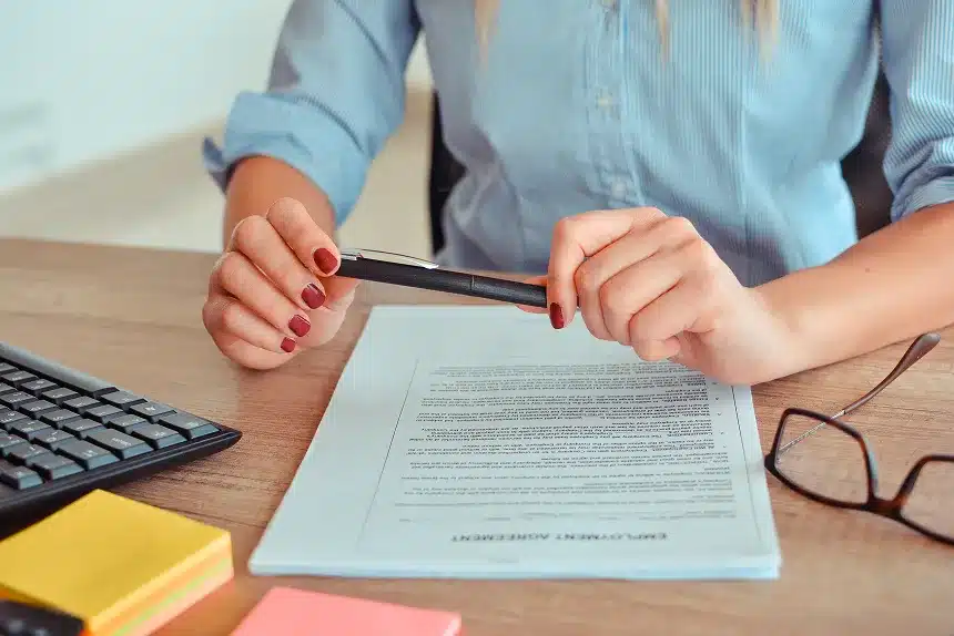 A woman writes on a piece of paper while holding a pen, focused on her task.