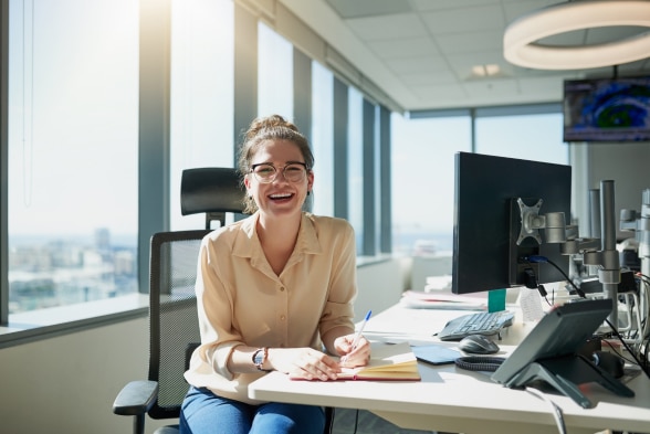 A woman seated at a desk in a professional office environment, focused on her work.