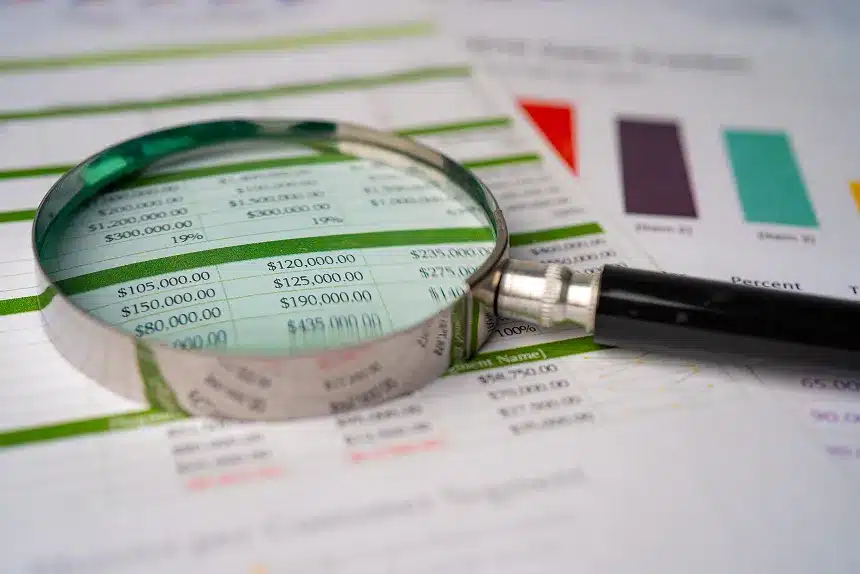 A magnifying glass placed on top of financial documents, highlighting details for closer examination.