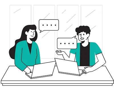 Two people sit at a table with laptops, smiling and chatting. Speech bubbles above suggest conversation. Large windows in the background.