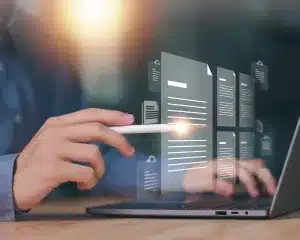 A man working on a laptop, reviewing documents displayed on the screen.