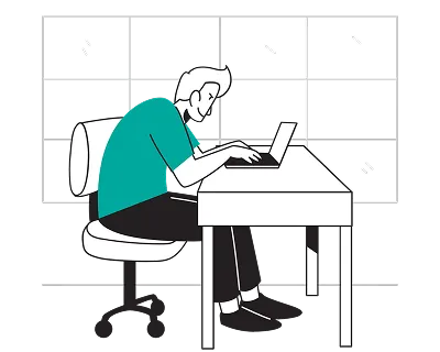 A man sitting at a desk, focused on his laptop, with a notepad and pen beside him.