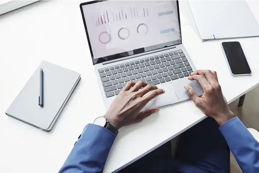 A person in a suit is focused on typing on a laptop, engaged in work or communication.