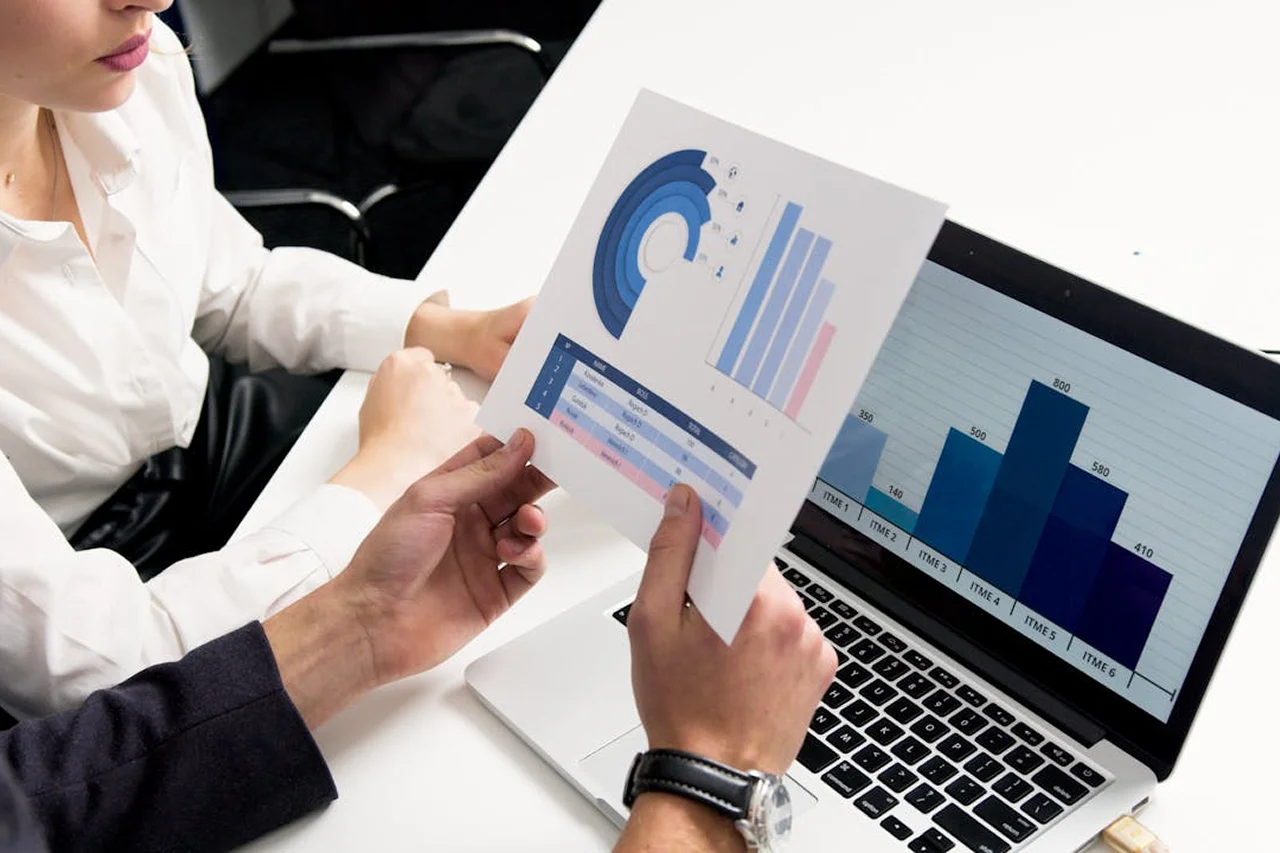 Business professionals analyzing graphs displayed on a laptop during a meeting.