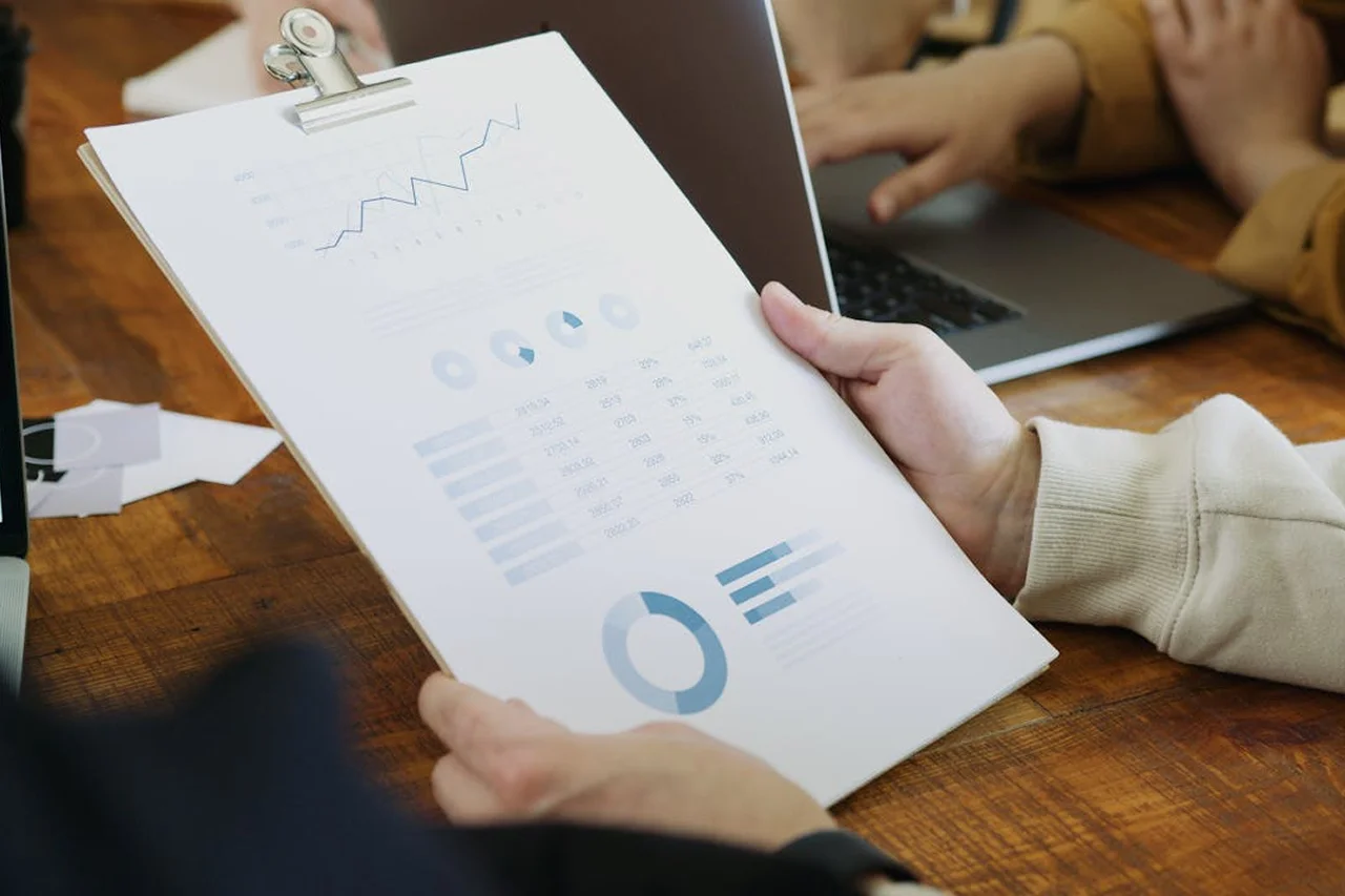 A person holding a clipboard displaying various graphs and data visualizations.