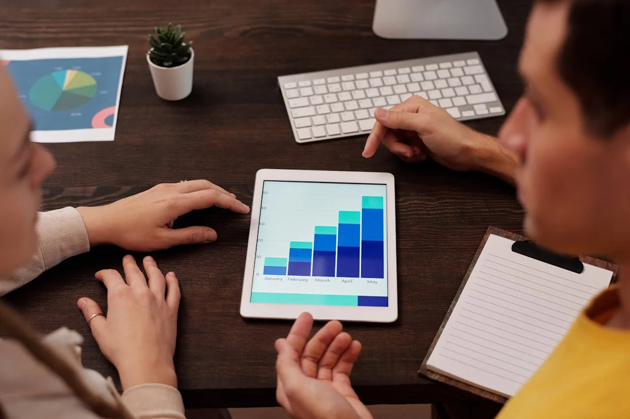 Two people are analyzing graphs displayed on a tablet together.
