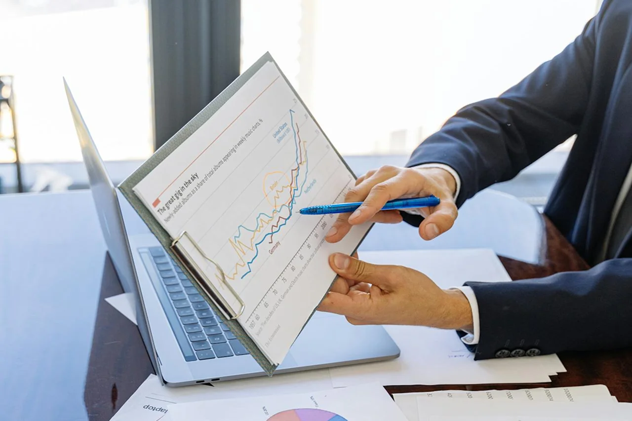 A man in a suit examines a chart displayed on his laptop, focusing intently on the data presented.