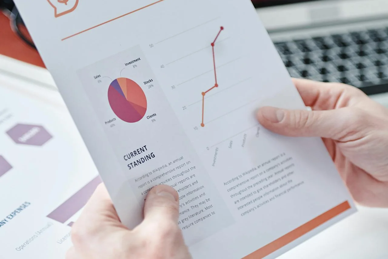 A person holds a document featuring various graphs and charts for analysis or presentation.