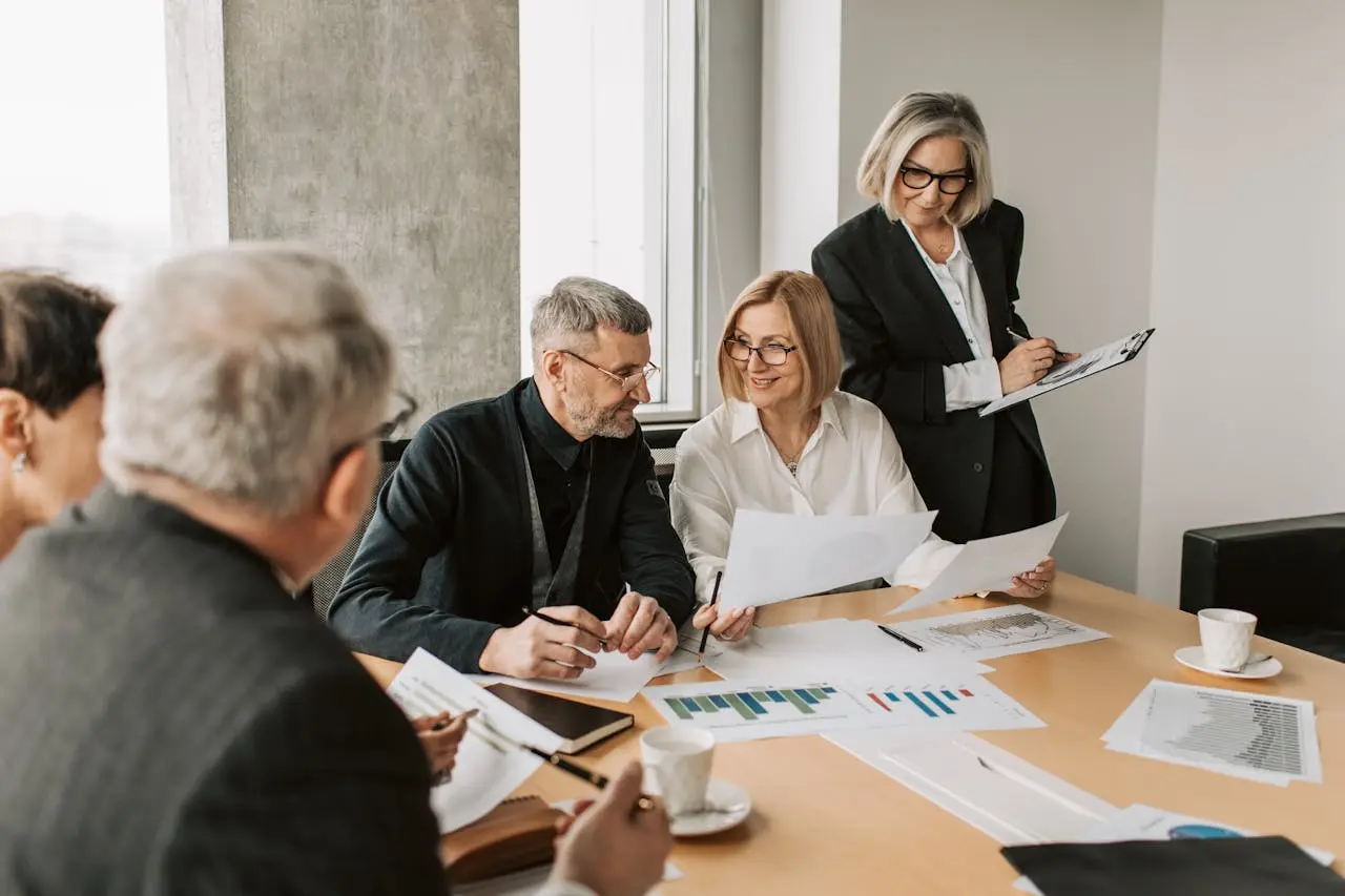 Business professionals engaged in discussion around a conference table in a modern meeting room.